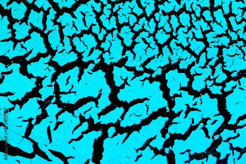 Cracked surface with blue paint on a black background, the effect of craquelure paint. Blue texture of antique design in bright color.