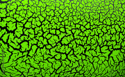 The cracked surface of green paint on a black background, the effect of craquelure paint. Green texture of antique design in bright color.
