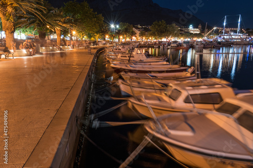 Waterfront promenade and moored boats in tourist resort Baska Voda on Adriatic sea coast in Croatia, at night in summer