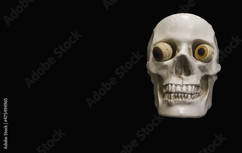 Clay skull on a black background. Cheerful eyes on the skull