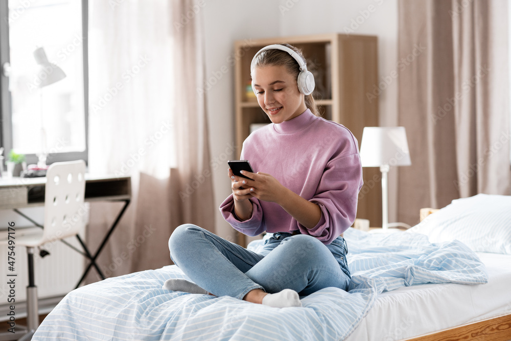 technology and people concept - happy smiling girl in headphones with smartphone at home technology and people concept - happy smiling girl in headphones with smartphone at home