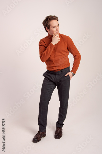 Successful businessman posing while standing against white white background. A man in a brown sweater.