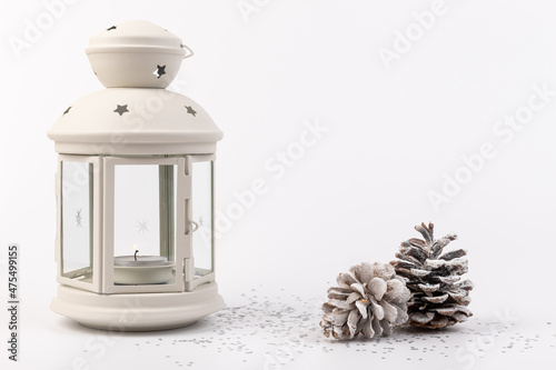 White lantern with candle inside and Christmas decoration on white background. Copy space.
