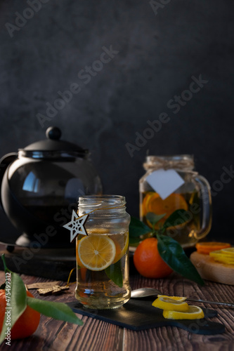 Teapot with hot citrus tea from oranges, lemons and limes, healthy drink, rustic background