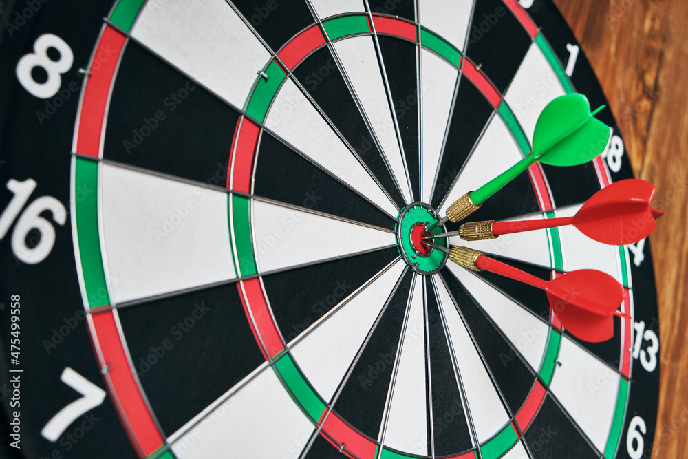 Concept of competition and goal achievement.Achieving goals in business and life.Dartboard with three darts stuck right center of target. Concept of competition and goal achievement.Achieving goals in business and life.Dartboard with three darts stuck right center of target.
