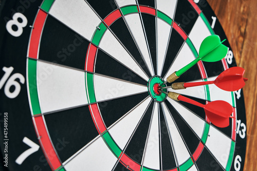 Concept of competition and goal achievement.Achieving goals in business and life.Dartboard with three darts stuck right center of target.