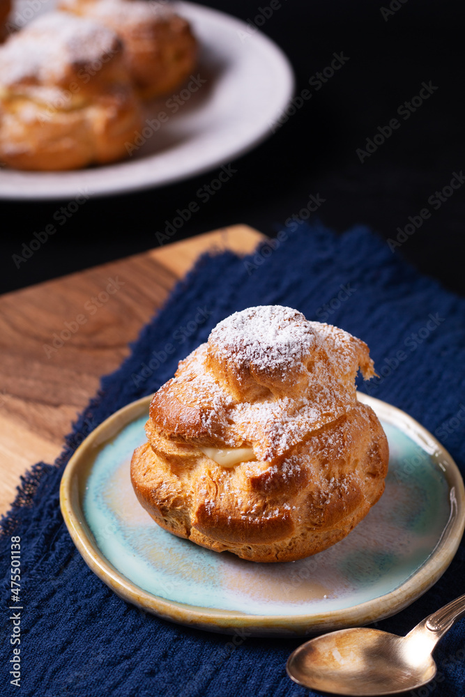 Food concept Homemade fresh baked Choux a la creme, Cream Puff, Choux Cream in white ceramic plate on black background with copy space Food concept Homemade fresh baked Choux a la creme, Cream Puff, Choux Cream in white ceramic plate on black background with copy space