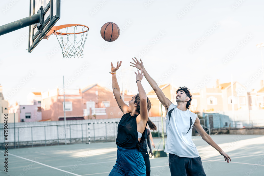 Woman jumping while throwing a ball into a basket playing basket