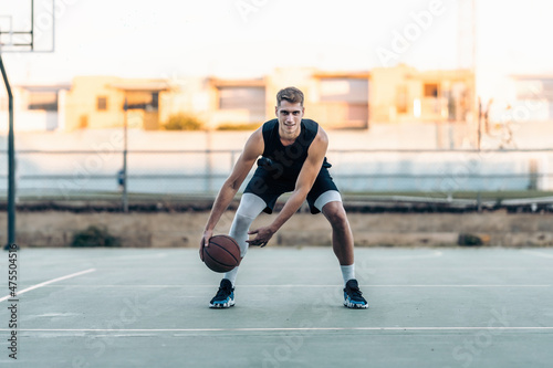 Basketball player bouncing the ball on an outdoor court