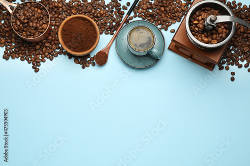 Flat lay composition with ground coffee and roasted beans on light blue background, space for text