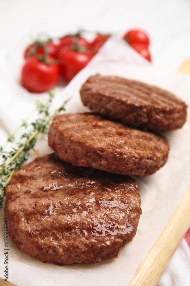 Wooden board with tasty grilled hamburger patties on table, closeup