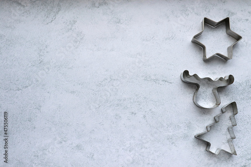 Christmas cookie cutters in star, christmas tree, deer shape on gray concrete background with copy space. Christmas frame, border, background

