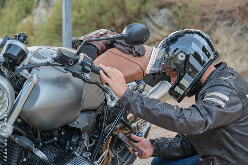 Biker calling with his mobile phone to the motorcycle insurance company Biker calling with his mobile phone to the motorcycle insurance company