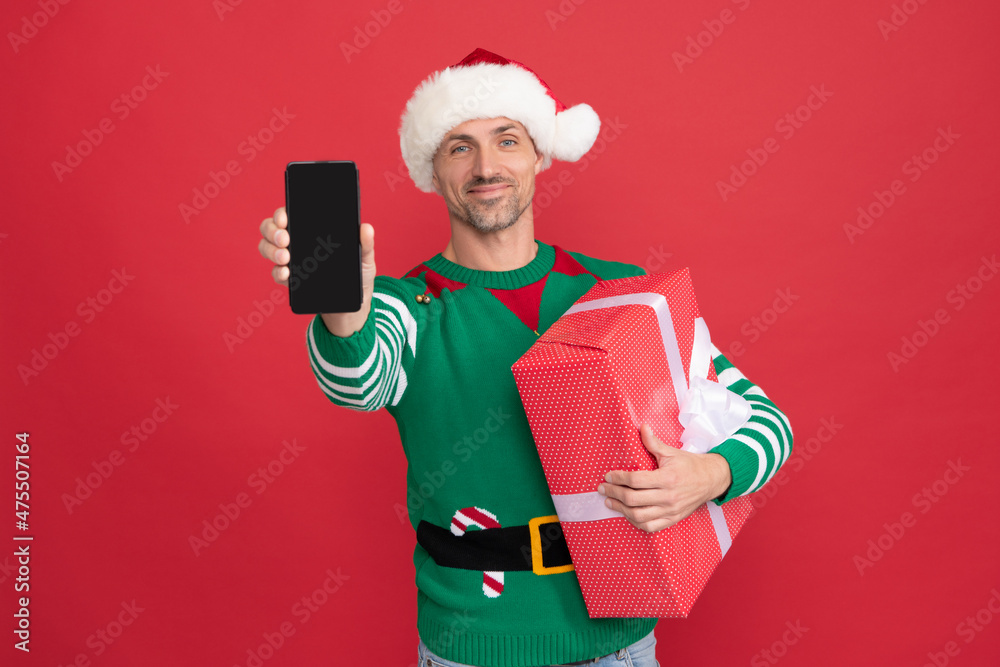 happy elf man in santa claus hat presenting smartphone. christmas advertisement. happy elf man in santa claus hat presenting smartphone. christmas advertisement.