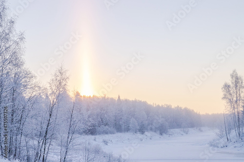 Beautiful winter landscape. Sunrise on a frozen river. The rising sun is like a candle. Trees are covered with hoarfrost 