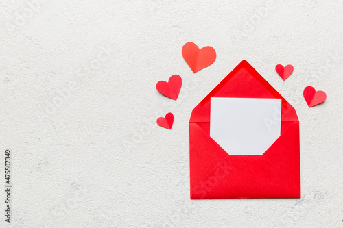 Red paper envelope with empty white card and heart on colored background. top view valentines day concept © sosiukin