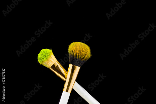 Two white with gold makeup brushes on a black background. Powder brush. close-up