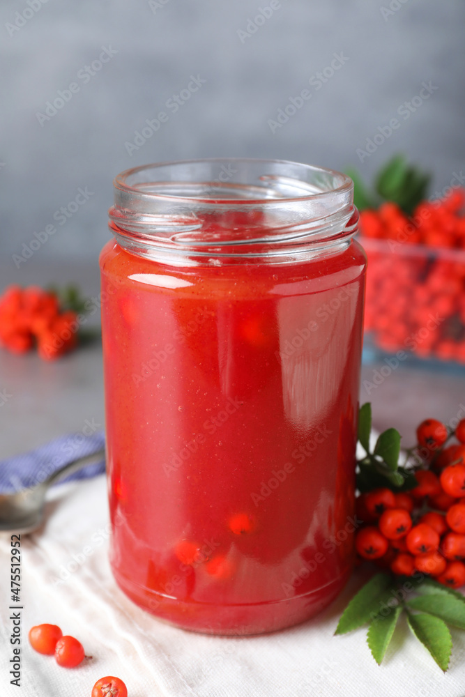 Delicious rowan jam in glass jar on grey table Delicious rowan jam in glass jar on grey table