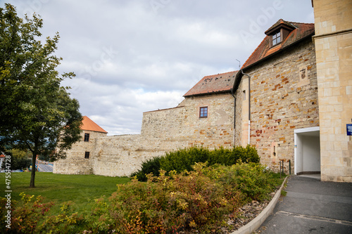 Louny, Czech Republic, 19 September 2021: Zatec Gate with wall and prismatic bastions, medieval fortification complex with wooden corridor under roof in autumn day, Latin inscriptions on front facade