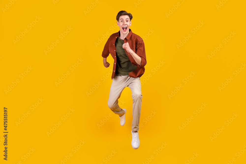 Full size photo of young crazy man amazed shock jump run hurry isolated over yellow color background