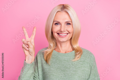 Photo of nice aged blond lady show v-sign wear grey pullover isolated over pink color background © deagreez