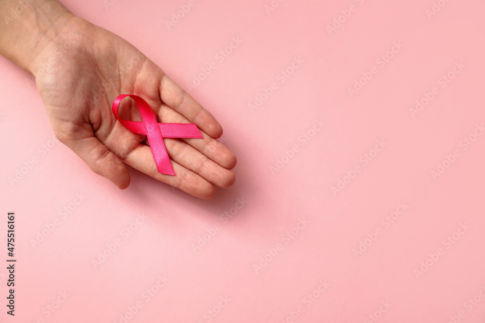 Woman holding pink ribbon on color background, top view with space for text. Breast cancer awareness concept Woman holding pink ribbon on color background, top view with space for text. Breast cancer awareness concept