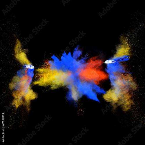 Blue and yellow bizarre forms of powder paint explode in front of a black background to give off fantastic multi colors and forms.