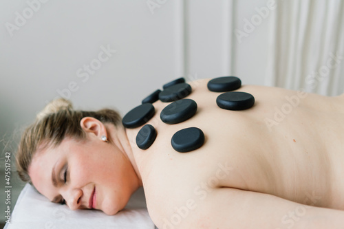 Plump woman getting hot stones arm massage in spa salon. Therapy, wellness and relaxation concept
