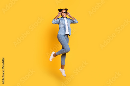 Full size profile side photo of young cheerful african lady jump eyewear energetic isolated over yellow color background