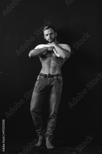young man, brutal appearance, with a beautiful torso, bodybuilder, in the studio on a black background, BW photo