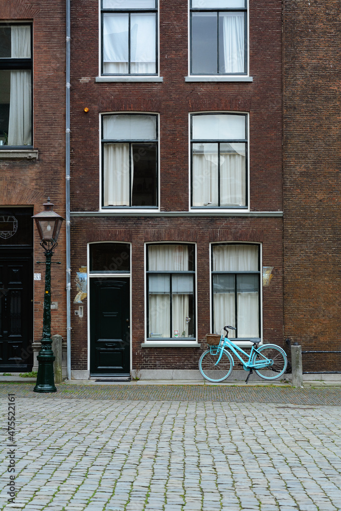 A blue bicycle is standing on a Dutch street. Old classic holland street with a blue bike. Typical holland street