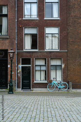 A blue bicycle is standing on a Dutch street. Old classic holland street with a blue bike. Typical holland street © Anastasia Pestova