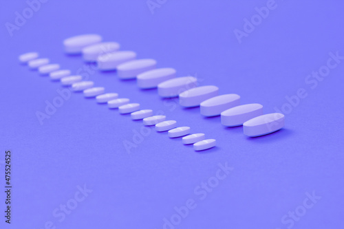 Trendy Color of the year 2022 Very Peri. White tablets on a lilac background close-up. Macro pills. Medical care for flu and colds. Protection from Covid19