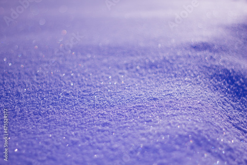 Trendy Color of the year 2022 Very Peri. Snowy white background. Texture of the snow. Shiny snow with bokeh and blurred background close-up. Lilac snow-covered field.