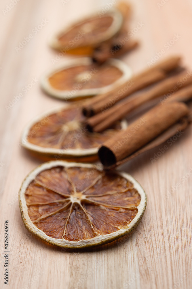 Rodelas de laranja desidratadas com paus de canela sobre superfície de madeira.