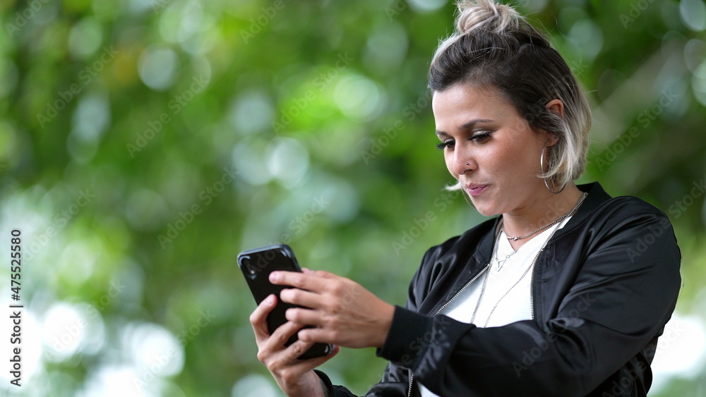 Young woman checking smartphone device outdoors smiling to good news Young woman checking smartphone device outdoors smiling to good news