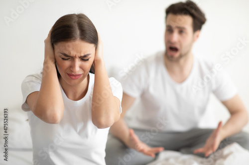 Unhappy Woman Covering Ears While Angry Husband Shouting In Bedroom