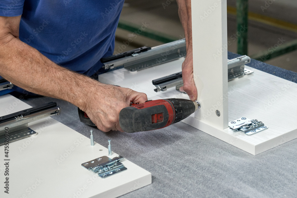 A worker assembles furniture at a factory. Industrial production of furniture. A worker assembles furniture at a factory. Industrial production of furniture.