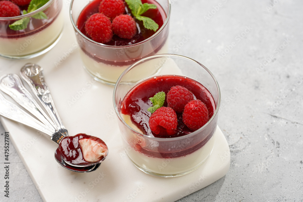 Italian dairy dessert panna cotta with raspberry jam, fresh raspberries and mint on marble board
