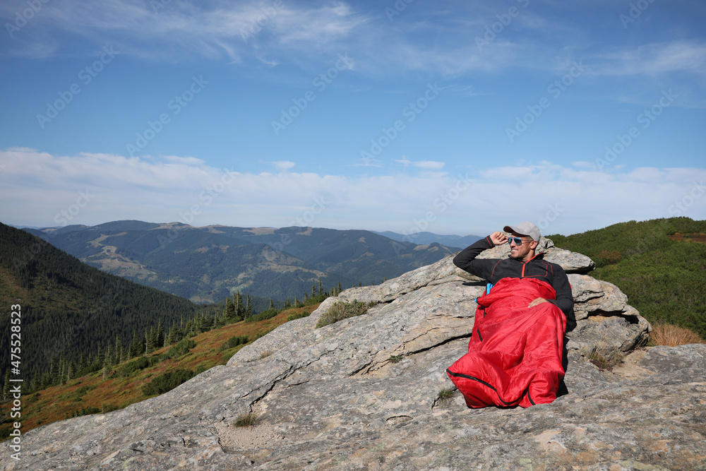 Fototapeta premium Tourist in sleeping bag on mountain peak