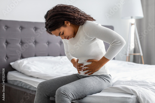 Black woman suffering from stomachache, touching her tummy photo
