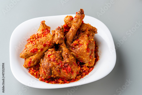 Ayam sambal balado or spicy fried chicken is Traditional food from Padang, West Sumatra. served on plate and isolated gray background. photo