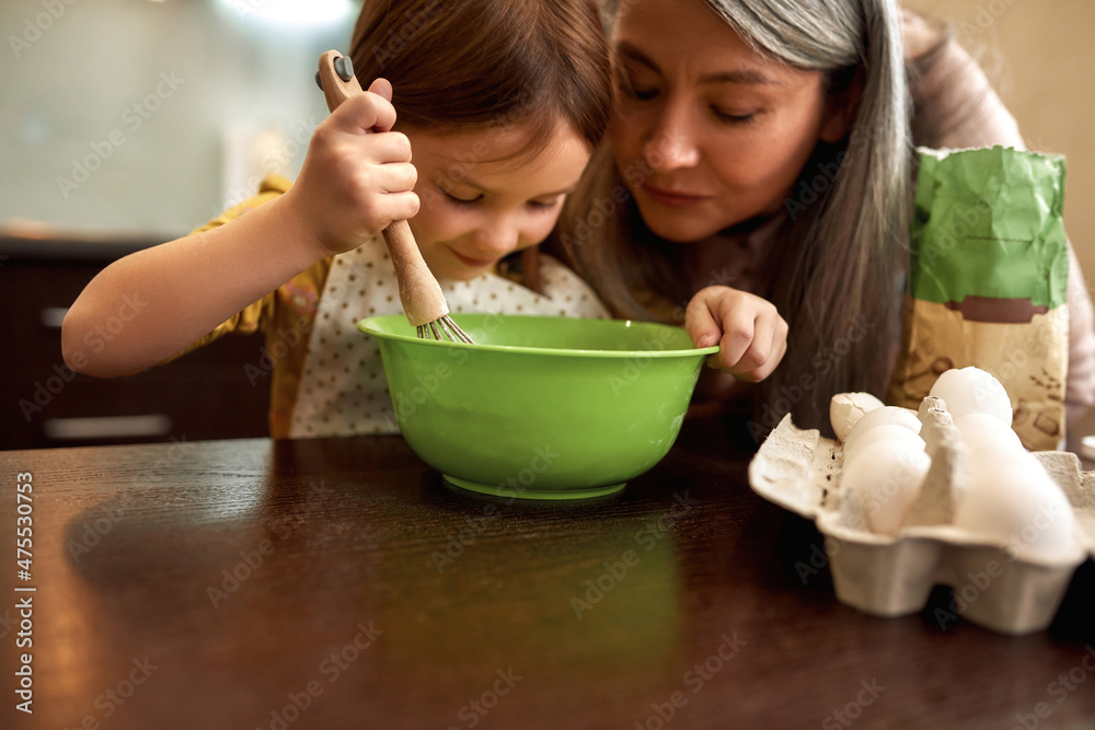 Smiling girl mixing dough in bowl with grandmother Smiling girl mixing dough in bowl with grandmother