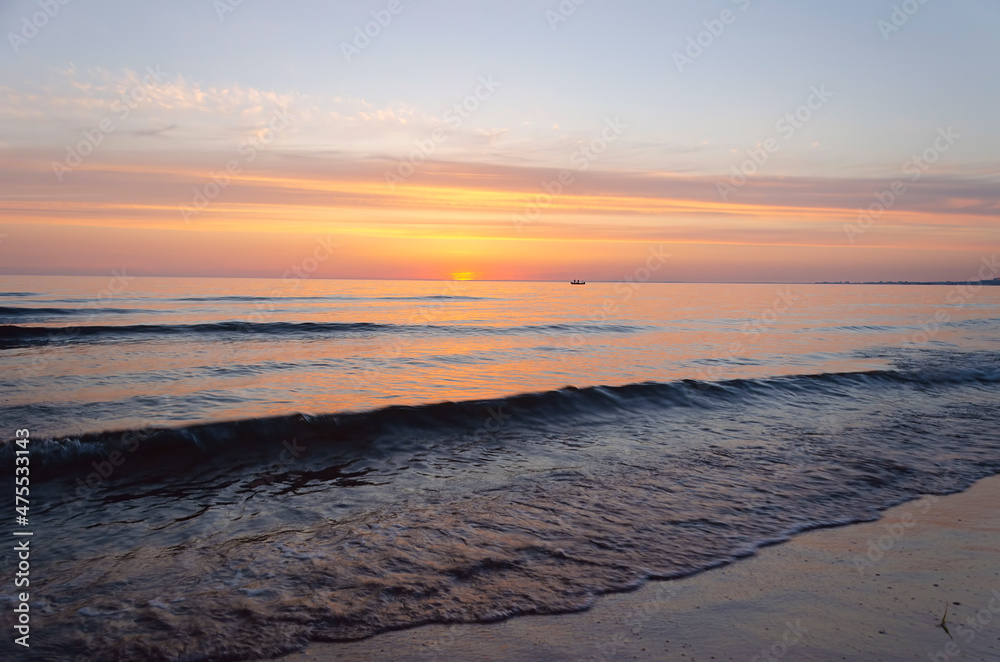 Obraz premium Fiery sunset on the sea. The silhouette of a ship is visible on the horizon