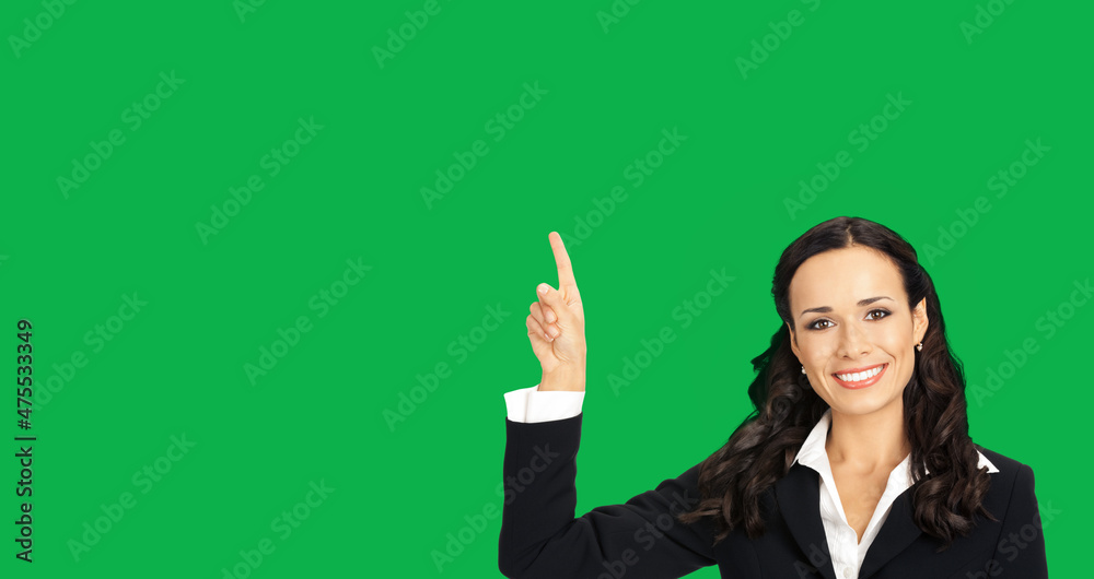 Young happy smiling woman in black confident suit, showing pointing at copy space. Business concept. Green colour background. Brunette businesswoman. Empty area for text. Young happy smiling woman in black confident suit, showing pointing at copy space. Business concept. Green colour background. Brunette businesswoman. Empty area for text.