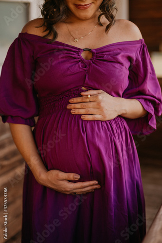 pregnant woman in purple dress holding her belly 