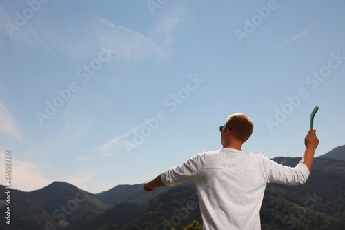 Man throwing boomerang in mountains on sunny day, back view. Space for text © New Africa