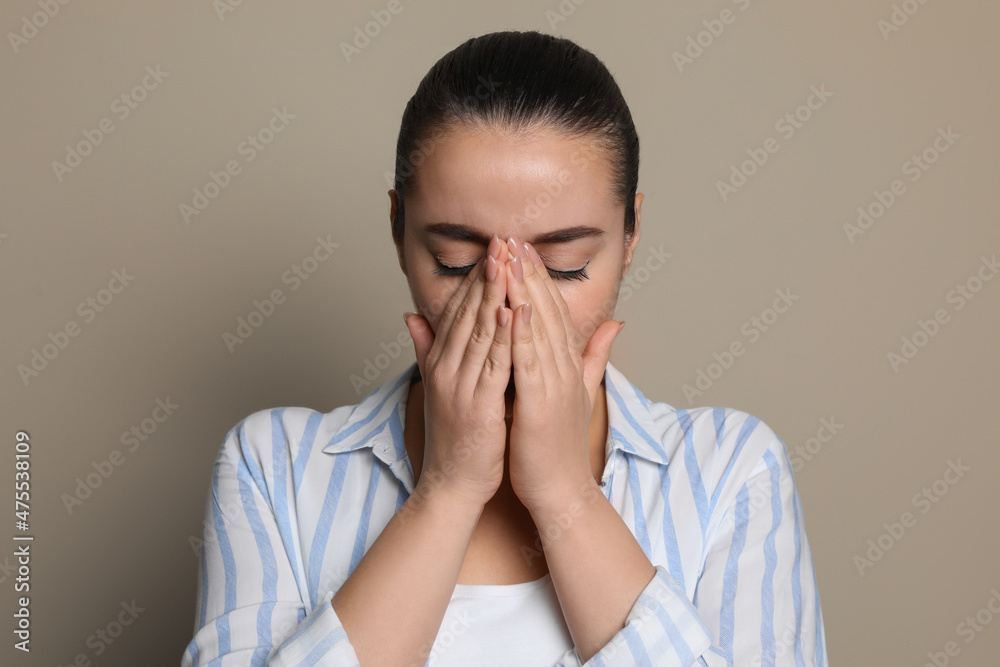 Young woman suffering from headache on beige background Young woman suffering from headache on beige background