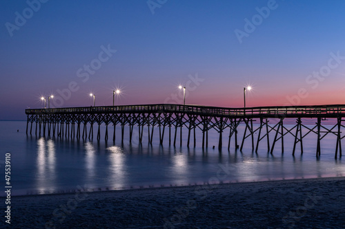 Fishing pier silhouette sunset blue hour orange and blue-sky lights shimming on the blurred waves Horizontal Photo  Photograph Holden Beach NC 