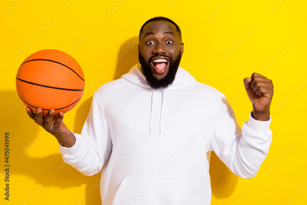 Photo of celebrate millennial beard man yell play basketball wear white hoodie isolated on yellow color background Photo of celebrate millennial beard man yell play basketball wear white hoodie isolated on yellow color background